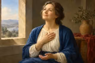 A peaceful woman holds a hand over her heart in a softly lit room.