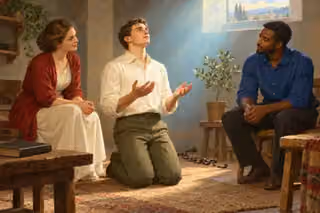 Oil painting of a young man kneeling with open hands in pearl-blue window light while two friends sit beside him; a broken chain, potted olive sapling and unmarked book suggest inward freedom and growth.
