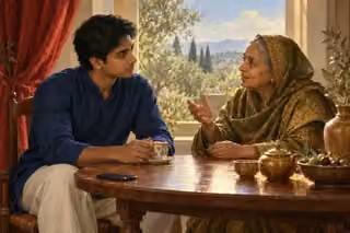 A young man listens attentively as an elderly woman speaks across a quiet tea table.