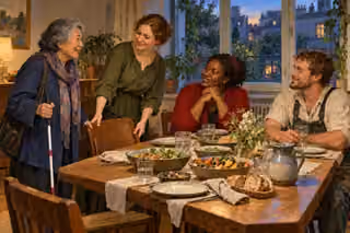 A host welcomes guests of modest means and a guest with a mobility cane to a generous shared supper.
